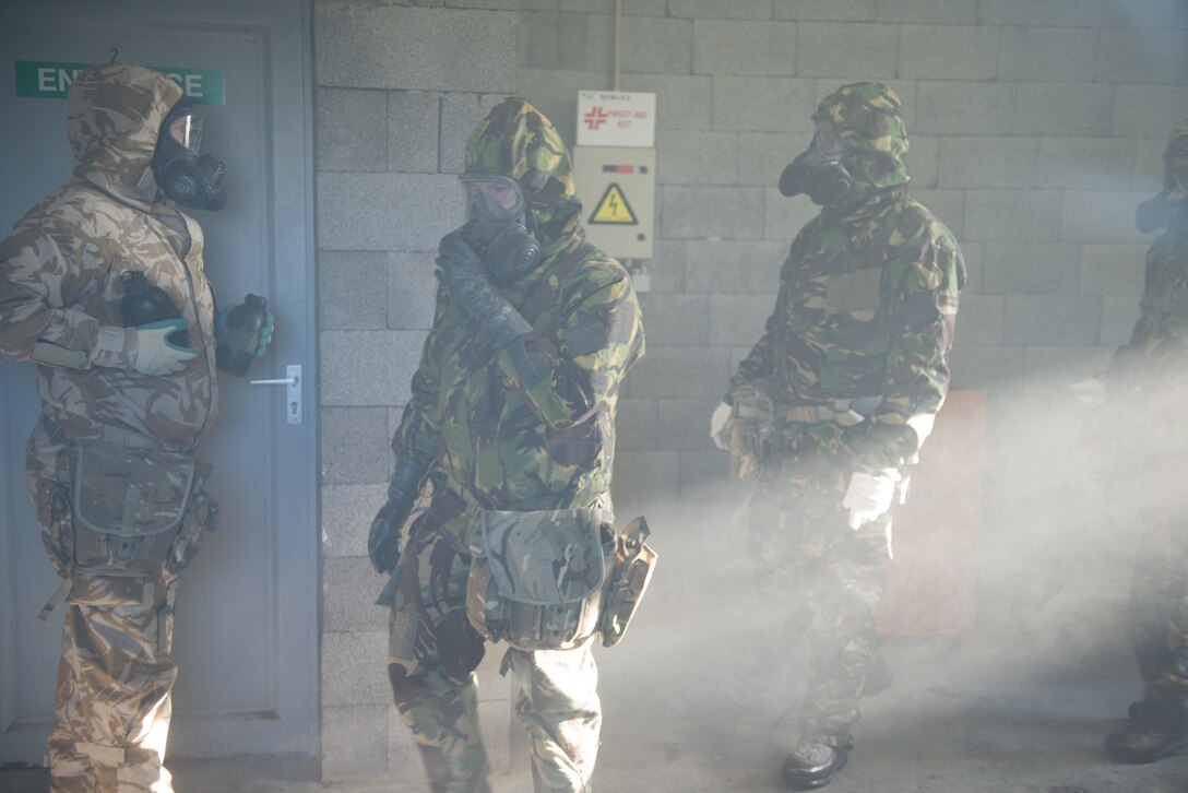 Members of the British armed forces, assigned to different NATO units, walk and adjust their general service respirators inside the U.S. Army Training Support Center Benelux chemical, biological, radiological and nuclear chamber on Chievres Air Base, Belgium, Jan. 19, 2016. British forces assigned to NATO trained under supervision of the British Joint European Training Team. U.S. Army photo by Pierre-Etienne Courtejoie