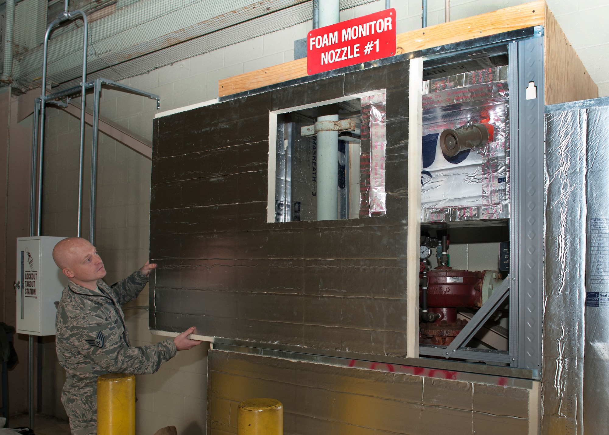 Staff Sgt. Casey Reed, 436th Civil Engineer Squadron, water and fuels systems maintenance removes a panel to show a fire suppression system inside a newly built insulation structure Feb. 2, 2016, inside Hangar 715 on Dover Air Force Base, Del. Five of these units were built around units inside this hangar. (U.S. Air Force photo/Senior Airman Zachary Cacicia)