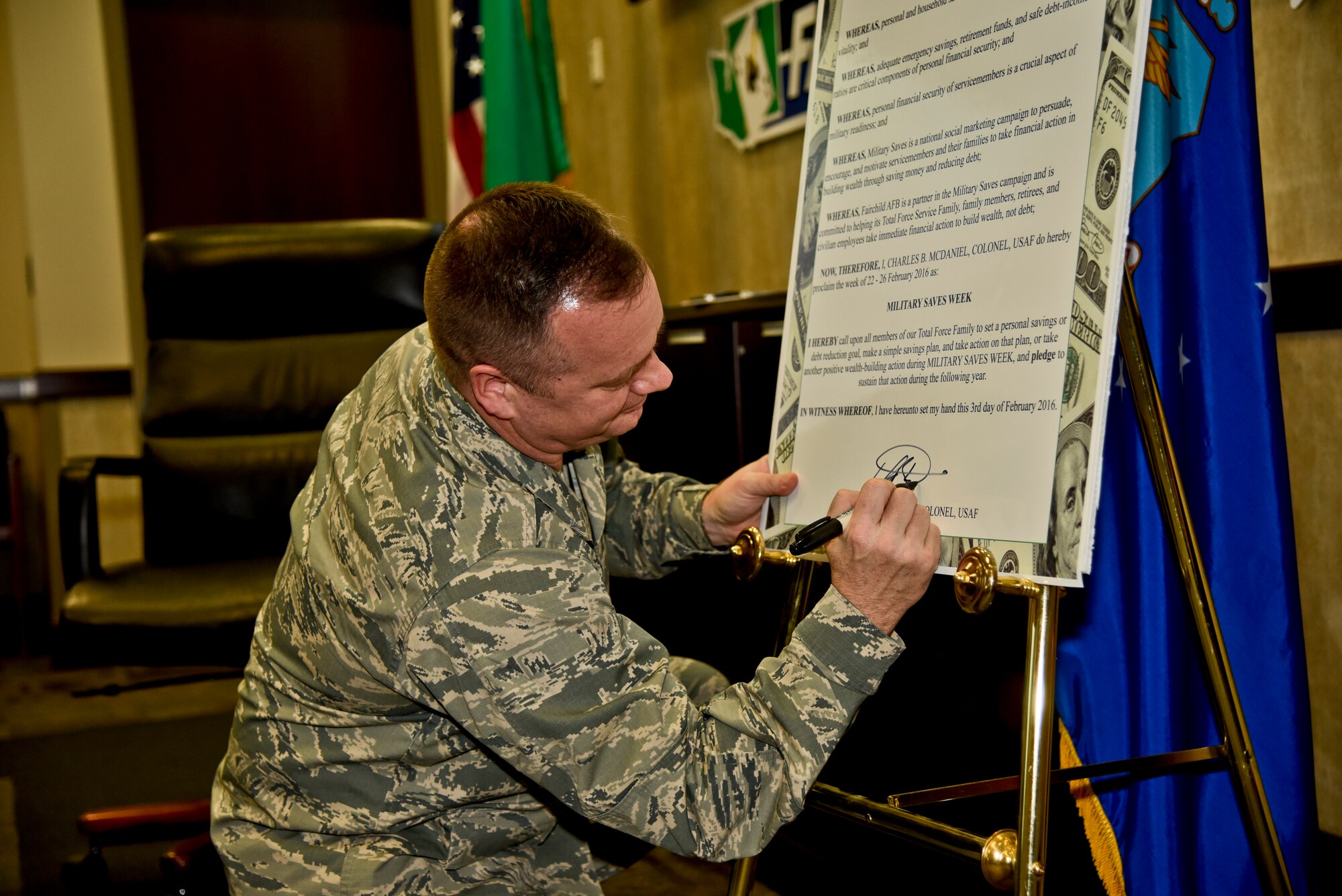 Col. Brian McDaniel, 92nd Air refueling Wing commander, signs the Military Saves Week proclamation Feb. 3, 2016, at Fairchild Air Force Base, Wash. Military Saves Week is an annual opportunity held in February for installations and organizations to promote good savings behavior and a chance for service members and their families to assess their own saving status. (U. S. Air Force photo/Airman 1st Class Taylor Bourgeous)