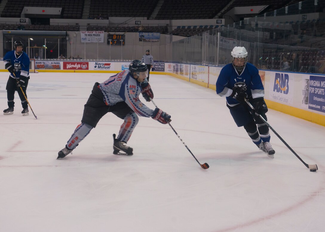 A member of the Langley Air Force Base Men’s Varsity hockey team, the Langley Raptors, eludes a defender from the U.S. Navy U.S.S. Abraham Lincoln’s hockey team during the “Air versus Sea” hockey game at the Norfolk Scope Arena in Norfolk, Va., Jan. 30, 2016. Over 400 spectators were in attendance for the game. (U.S. Air Force photo by Staff Sgt. J.D. Strong II)