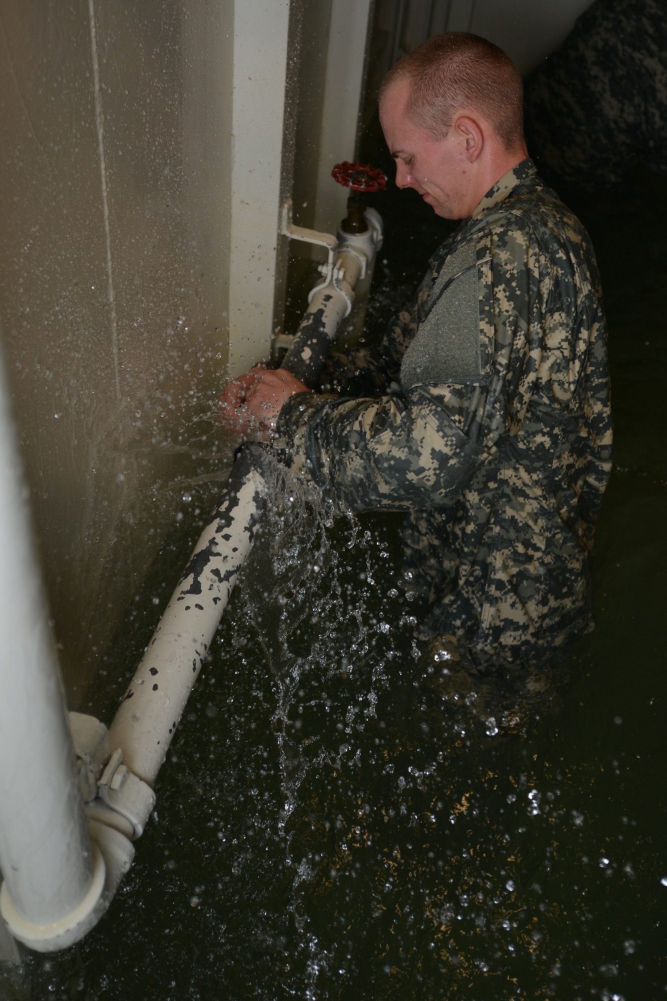 U.S. Army Pvt. Joseph McDermott, a student assigned to the Maritime Intermodal Training Department watercraft operator course, attempts to stop water from bursting out of a pipe during a simulation exercise at Fort Eustis, Va., Jan. 26, 2016. The students worked as an assembly to gather various materials used to stop water from sinking the training tank.  (U.S. Air Force photo by Staff Sgt. Natasha Stannard)