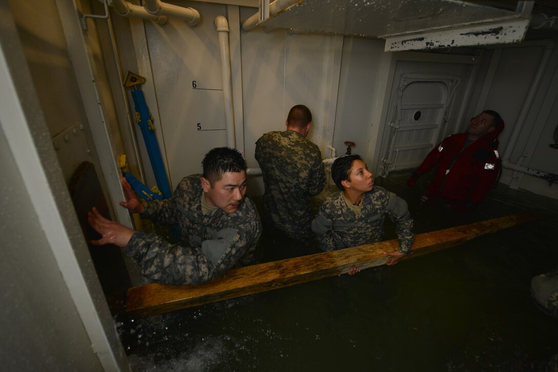 U.S. Army Pvt. Joseph McDermott, a student assigned to the Maritime Intermodal Training Department watercraft operator course, attempts to stop water from bursting out of a pipe during a simulation exercise at Fort Eustis, Va., Jan. 26, 2016. The students worked as an assembly to gather various materials used to stop water from sinking the training tank.  (U.S. Air Force photo by Staff Sgt. Natasha Stannard)