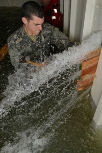 U.S. Army Pvt. Brent Bates, a student assigned to the Maritime Intermodal Training Department watercraft operator course, hammers wedges into a rupture during a simulation exercise at Fort Eustis, Va., Jan. 26, 2016.  The wedges were used to stop water from bursting through the ruptures during the damage control tank simulator training. .  (U.S. Air Force photo by Staff Sgt. Natasha Stannard)