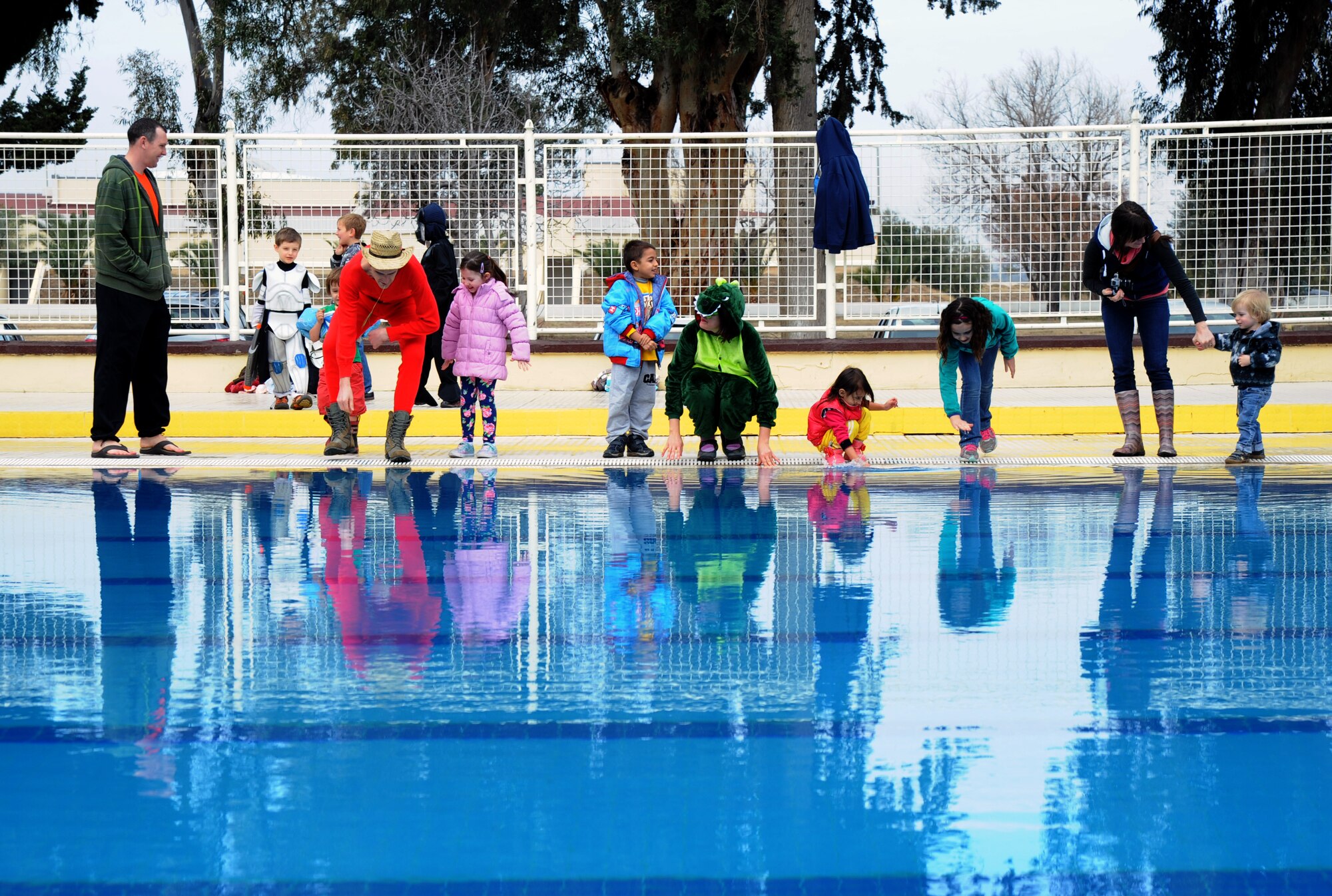 Polar plunge onlookers and participants feel the water as some prepare to jump into the base pool during the polar plunge event Jan. 20, 2016, at Incirlik Air Base, Turkey. The Polar Plunge is an annual event held at Incirlik AB, which gives members an opportunity to dress up in costumes and take a plunge into the cold water of the base pool. (U.S. Air Force photo by Airman 1st Class Daniel Lile/Released)