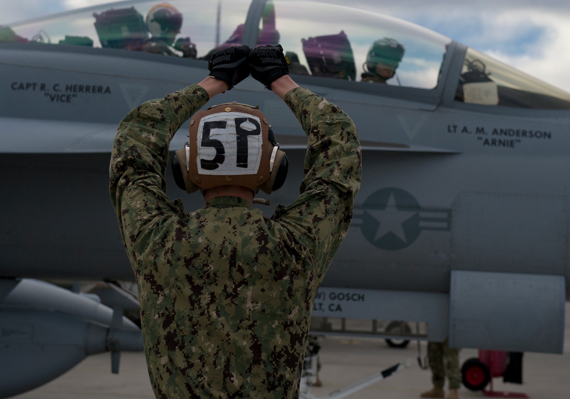 United States Navy Airman Ryan Smith, VAQ-138 plane captain from Naval Air Station Whidbey Island, Wash., marshals in an EA-18G Growler during Red Flag 16-1, Jan. 29, 2016 at Nellis AFB, Nev. Red Flag brings together units from all over the world including multiple military branches and countries. One thing they all have in common is the need for experienced maintainers. (U.S. Air Force photo by Senior Airman Alex Fox Echols III/Released)