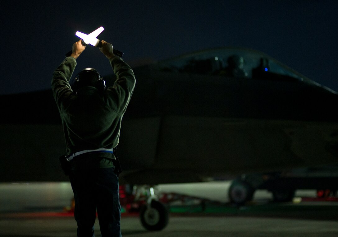 Senior Airman Nigel Williams, 95th Aircraft Maintenance Unit crew chief, marshals an F-22 Raptor during Red Flag 16-1, Jan. 26 at Nellis AFB, Nev. Integration is key at Red Flag, and Tyndall’s F-22s and Airmen join more than 130 aircraft and 3,000 personnel training during the exercise. (U.S. Air Force photo by Senior Airman Alex Fox Echols III/Released)  