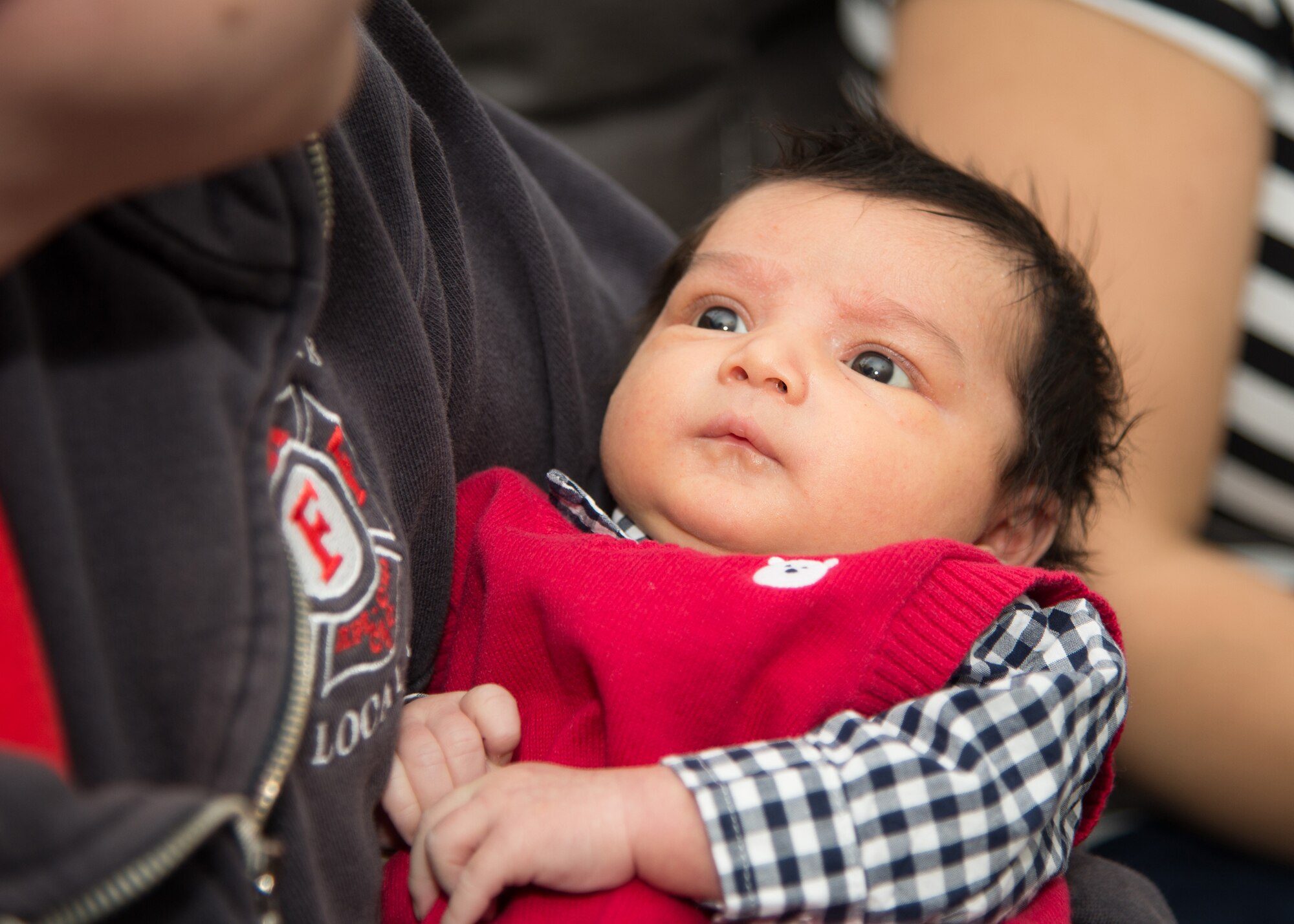 Newborn Christian Figueroa looks up at Kevin Tanguay during a reunion with three 66th Civil Engineering Division Fire and Emergency Services firefighters at Hanscom Air Force Base, Mass., Jan. 29. Christian was delivered in the family’s home unexpectedly by Tanguay, Keith Williams and Eric Vail-Naylor, following a dispatch for a woman in labor. (U.S. Air Force photo by Mark Herlihy)