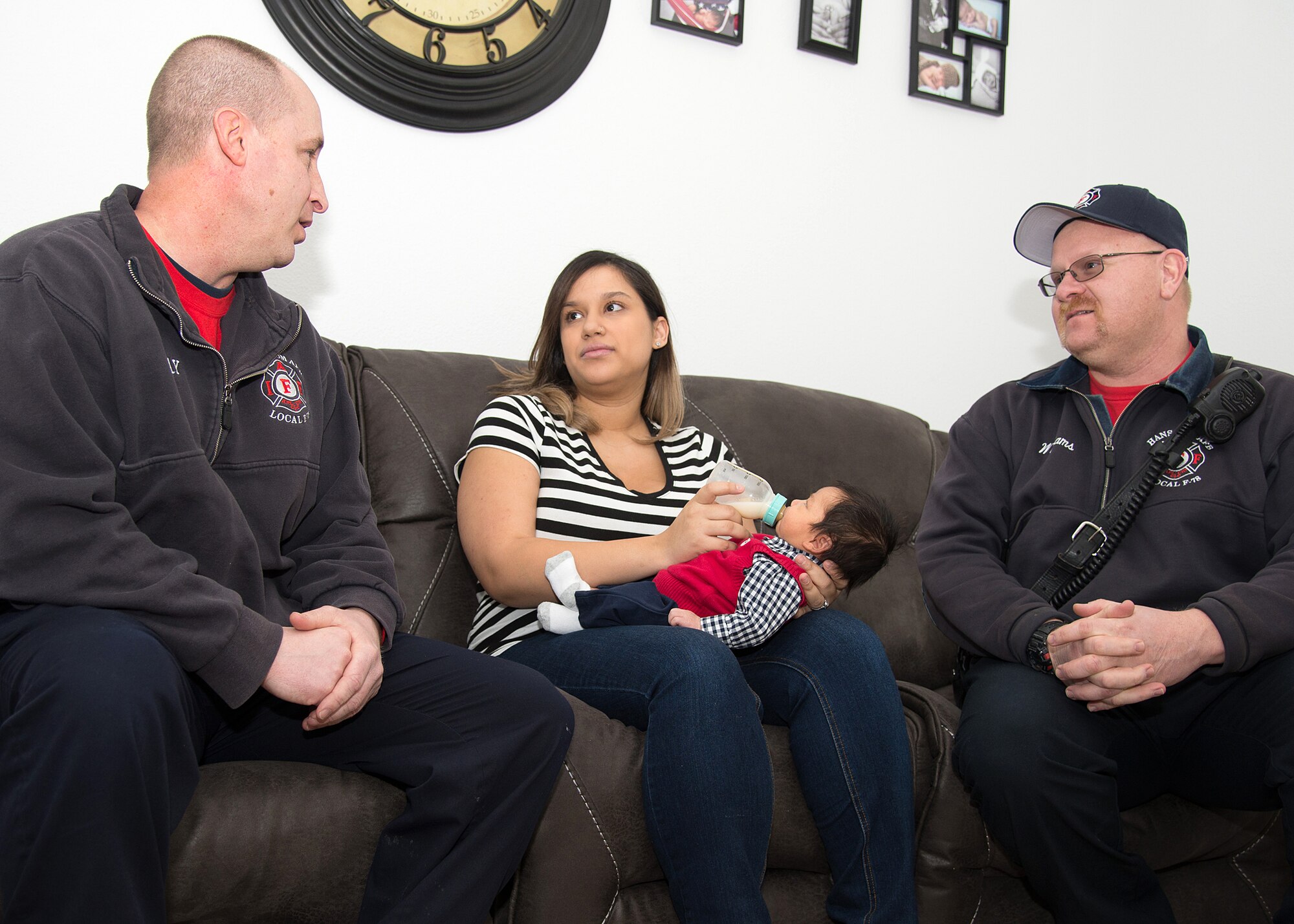 Amanda Figueroa holds her newborn son, Christian, during a reunion with Hanscom firefighters, Kevin Tanguay, left, and Keith Williams, inside her Hanscom Air Force Base, Mass., home, Jan. 29. The two Hanscom firefighters, along with the third firefighter in scene, Eric Vail-Naylor, were dispatched to the home for a woman in labor Jan. 5 that resulted in the three firefighters delivering the baby in an upstairs bedroom. (U.S. Air Force photo by Mark Herlihy)