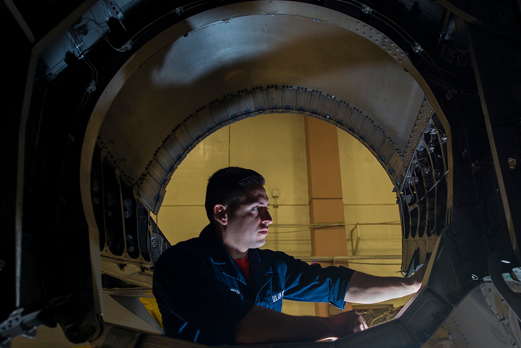 U.S. Air Force Airman 1st Class Jorge Pauker, 18th Equipment Maintenance Squadron inspection section team member, inspects the back of an F-15 Eagle after the engine was pulled out Jan. 28, 2016, at Kadena Air Base, Japan. The aircraft is in phase, which is where it is pulled into a hangar and pulled apart to inspect every function of the aircraft, making sure it is in proper working order. (U.S. Air Force photo by Airman 1st Class Corey M. Pettis) 