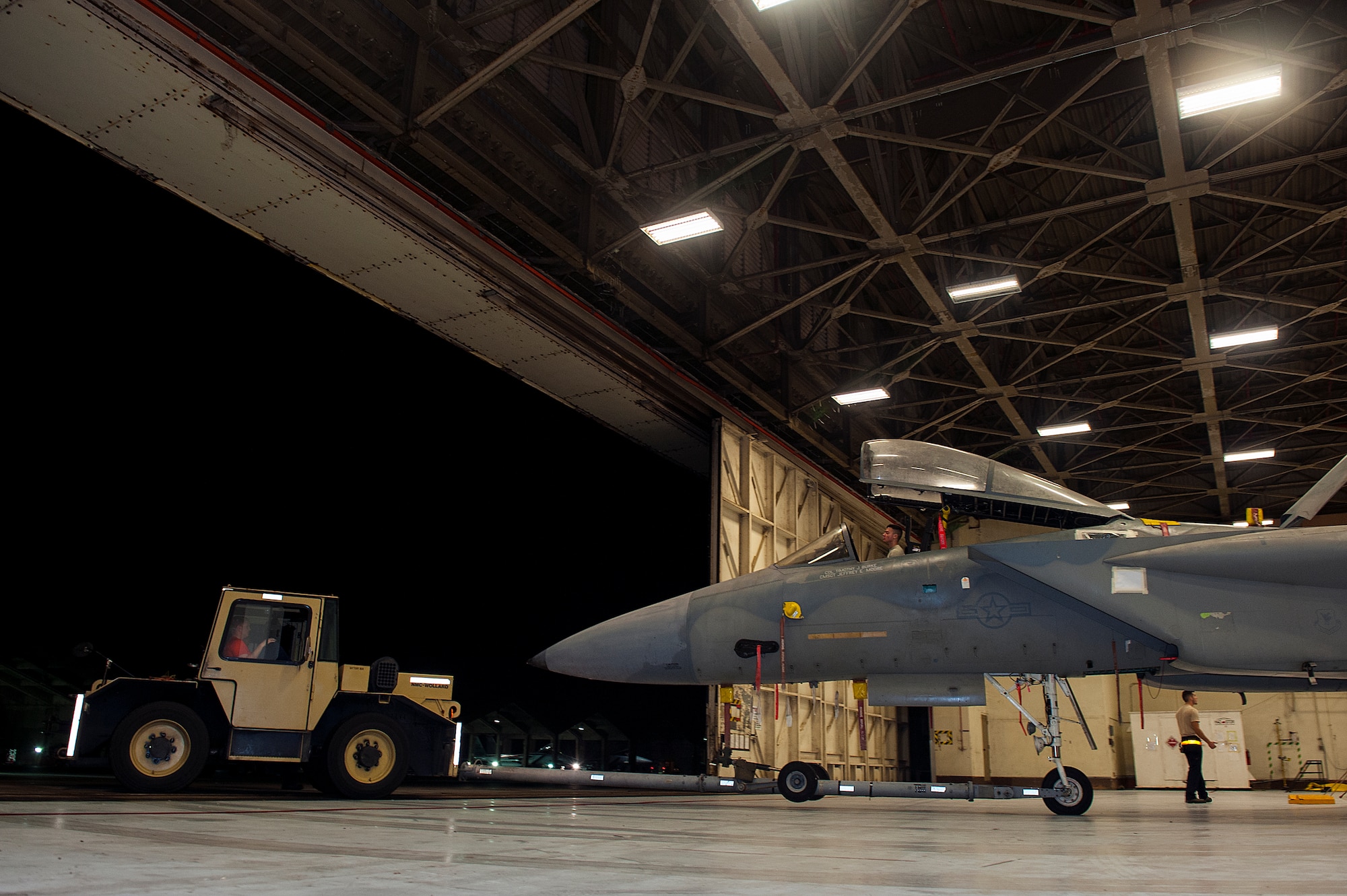 Members of the 18th Equipment Maintenance Squadron tow an F-15 Eagle into a hangar Jan. 29, 2016, at Kadena Air Base, Japan. Moving a 32,000 pound jet is a very delicate procedure, requiring skill, caution and focus. One Airman drives the towing vehicle while another sits in the cockpit. (U.S. Air Force photo by Airman 1st Class Corey M. Pettis)