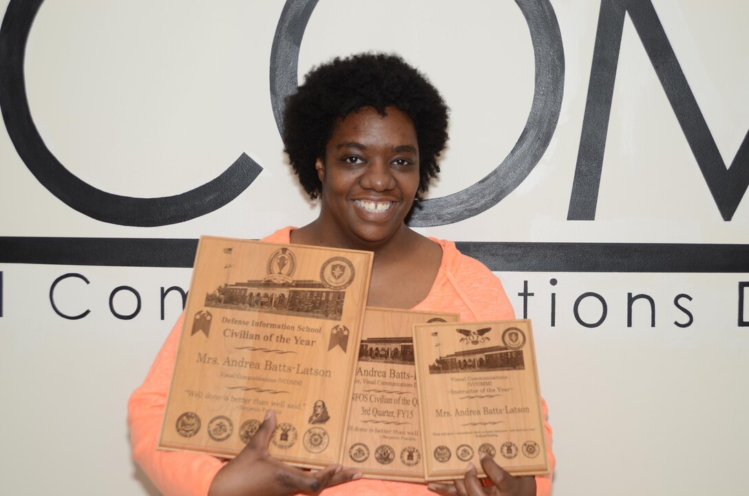 Andrea Batts-Latson stands in front of the Visual Communications Department wall at the Defense Information School with her 2015 awards. Batts-Latson won the third DINFOS Civilian of the Quarter, DINFOS 2015 Civilian of the Year and DINFOS Visual Communications Department Instructor of the Year awards.