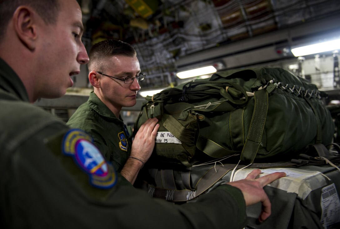 Air Force Senior Airman Brian Dixon and Staff Sgt. Kyle Mace inspect a container delivery system bundle on Pope Army Airfield, N.C., Feb. 3, 2016. Air Force photo by Staff Sgt. Marianique Santos