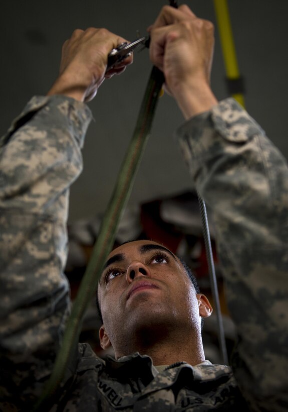 Army Spc. Quincy Howell clips off excess material while attaching a container delivery system bundle to a line on an Air Force C-17 Globemaster III aircraft on Pope Army Airfield, N.C., Feb. 3, 2016. Air Force photo by Staff Sgt. Marianique Santos