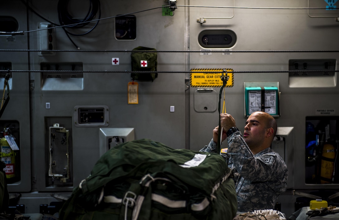 Army Spc. Arquimedes Duran attaches a container delivery system bundle to a line on a C-17 Globemaster III on Pope Army Airfield, N.C., Feb. 3, 2016. Duran a parachute rigger assigned to the 11th Quartermaster Company, 264th Combat Sustainment Support Battalion, 82nd Sustainment Brigade. Air Force photo by Staff Sgt. Marianique Santos
