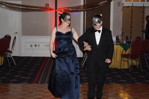 Sgt. Elizabeth Orrie, Defense Intelligence Agency, and her date, former Marine Alex Pereira, walk in the parade that began the Headquarters and Service Battalion Mardi Gras Masquerade Ball Jan. 29.