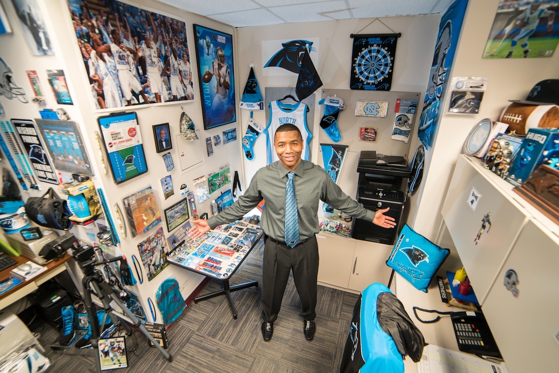 Sidney A. Williams Jr., the support services supervisor for the Defense Information School on Fort Meade, stands in his office at the school. Williams, who grew up in North Carolina, has filled the office with Carolina Panthers memorabilia, including a picture of a Panthers player that his son, Michael D. Williams, now 19, drew for him when he was 10, and a framed jersey autographed by Cam Newton, the star quarterback for the team. 