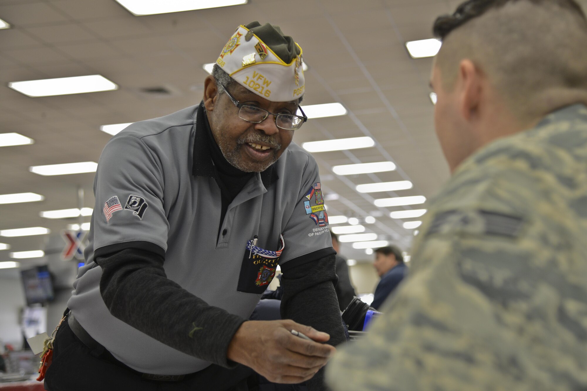 Retired Tech. Sgt. Ron Davis, Veterans of Foreign Wars senior vice commander for Korea, explains the benefits of becoming a VFW member to an active-duty Airmen in the Exchange during the Retiree Appreciation Day at Osan Air Base, Republic of Korea, Feb. 4, 2016. Retirees living and working in the vicinity of Osan AB showed up to learn about and enjoy the benefits available to retirees and veterans. (U.S. Air Force photo by Tech. Sgt. Travis Edwards/Released)