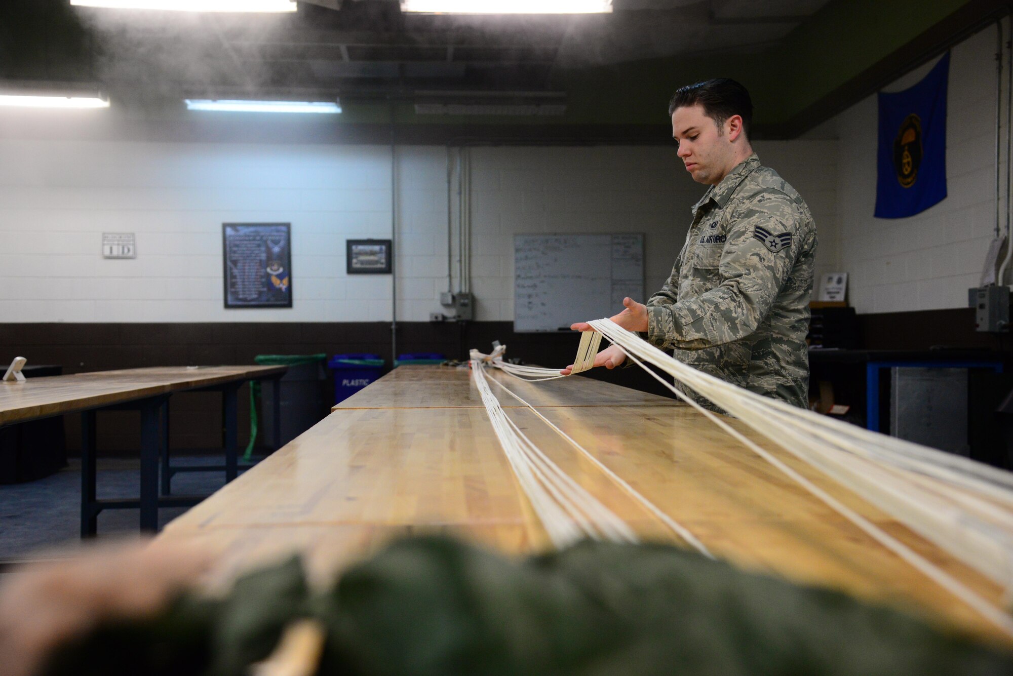 Senior Airman Phillip Conley, 51st Operations Support Squadron aircrew flight equipment specialist, inspects the lines on a parachute at the AFE main shop on Osan Air Base, Republic of Korea, Jan. 26, 2016. The inspection is part of the annual periodic review of the ejection seat, pilot recovery parachute and survival kit performed by the Airmen. (U.S. Air Force photo by Staff Sgt. Amber Grimm/Released)