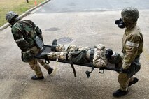 Tech. Sgt. Eric Busse (left), 4th Logistics Readiness Squadron readiness supervisor, and Capt. John Whitehouse (right), 4th LRS flight deployment distribution flight commander, carry Staff Sgt. Melissa King, 4th LRS readiness supervisor, after she suffered a simulated leg injury, Feb. 2, 20116, at Seymour Johnson Air Force Base, North Carolina. Airmen across the base demonstrated their ability to survive and operate in a chemical environment for wing inspection team members. (U.S. Air Force photo/Airman Shawna L. Keyes)