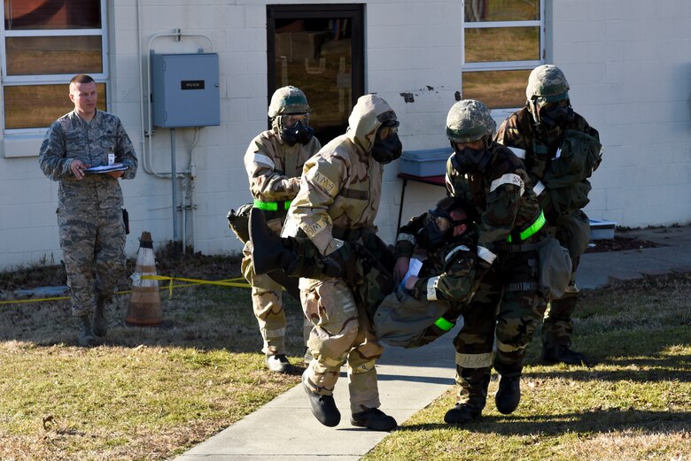 Airmen from the 4th Logistics Readiness Squadron fuels service center transport a simulated injured Airman while being evaluated by Tech. Sgt. Ricardo Visconti (left), 4th LRS quality assurance evaluator and wing inspection team member, during exercise Coronet Warrior 16-01, Feb. 1, 2016, at Seymour Johnson Air Force Base, North Carolina. Airmen had to evacuate the building during a simulated fire and care for their wounded. (U.S. Air Force photo/Airman Shawna L. Keyes)
