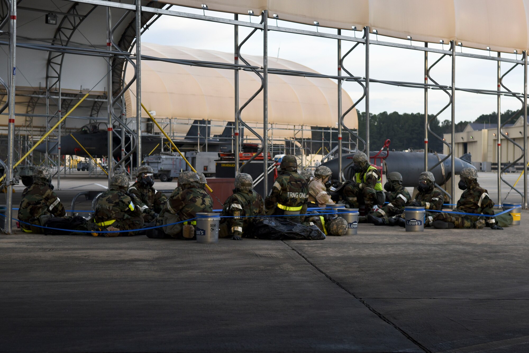 Airmen from the 4th Aircraft Maintenance Squadron huddle inside a simulated bunker during exercise Coronet Warrior 16-01, Feb. 1, 2016, at Seymour Johnson Air Force Base, North Carolina. Airmen working on the flightline donned mission oriented protective posture gear and conducted various simulations during the exercise. (U.S. Air Force photo/Airman Shawna L. Keyes)   
