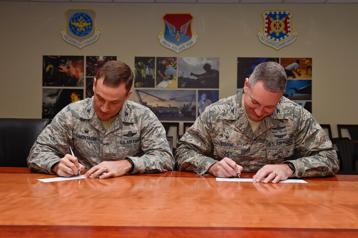 Col. John Lamontagne (left), the 437th Airlift Wing commander, and Col. Robert Lyman, the Joint Base Charleston commander, smile before signing their Air Force Assistance Fund contribution forms, Feb. 4, 2016, at Joint Base Charleston, S.C. The AFAF is an annual effort to raise contributions for four non-profit organizations which help Air Force members to include Airmen, dependents and surviving spouses. Each squadron on the installation has a unit AFAF representative, who has donation forms. (U.S. Air Force photo/Staff Sgt. Jared Trimarchi)