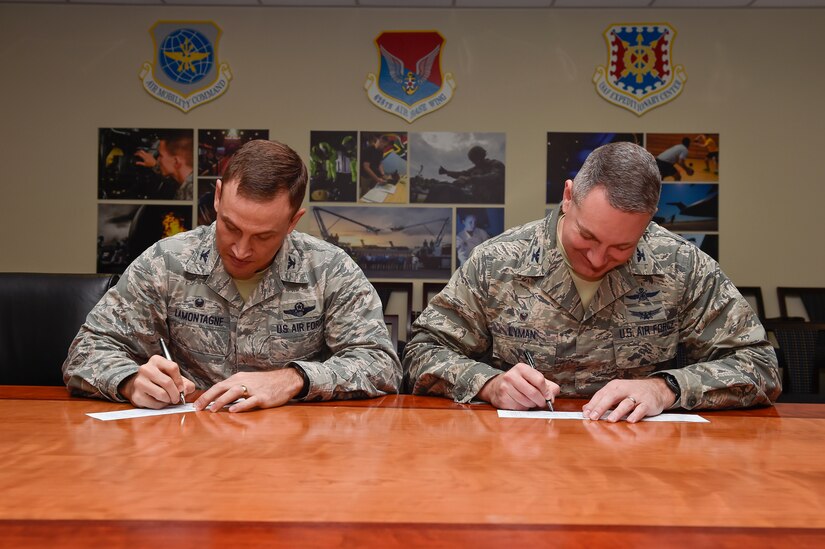 Col. John Lamontagne (left), the 437th Airlift Wing commander, and Col. Robert Lyman, the Joint Base Charleston commander, smile before signing their Air Force Assistance Fund contribution forms, Feb. 4, 2016, at Joint Base Charleston, S.C. The AFAF is an annual effort to raise contributions for four non-profit organizations which help Air Force members to include Airmen, dependents and surviving spouses. Each squadron on the installation has a unit AFAF representative, who has donation forms. (U.S. Air Force photo/Staff Sgt. Jared Trimarchi)