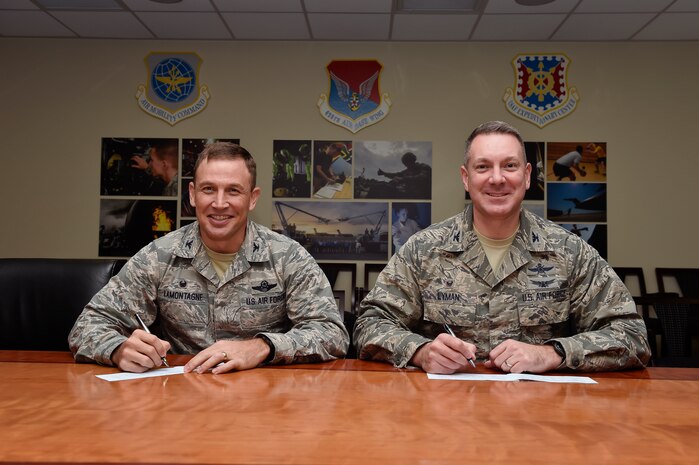 Col. John Lamontagne (left), the 437th Airlift Wing commander, and Col. Robert Lyman, the Joint Base Charleston commander, sign their Air Force Assistance Fund contribution forms, Feb. 4, 2016, at Joint Base Charleston, S.C. The AFAF is an annual effort to raise contributions for four non-profit organizations which help Air Force members to include Airmen, dependents and surviving spouses. Each squadron on the installation has a unit AFAF representative who has donation forms. (U.S. Air Force photo/Staff Sgt. Jared Trimarchi)
