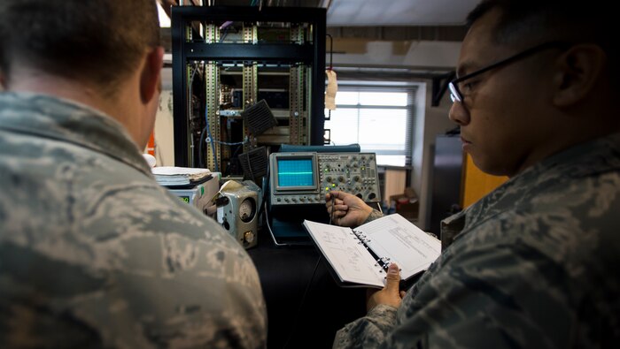 Staff Sgt. Michael Reyes, 437th Operations Support Squadron airfield systems technician, reads a technical order to Tech. Sgt. Shawn Arnett, 437th OSS airfield systems technician Jan. 27, 2016, at the command tower on Joint Base Charleston – North Auxiliary Air Field, S.C. This two-man team ensures that all of their airfield systems located at North Field work properly and provide any maintenece when needed. (U.S. Air Force photo/Senior airman Clayton Cupit)