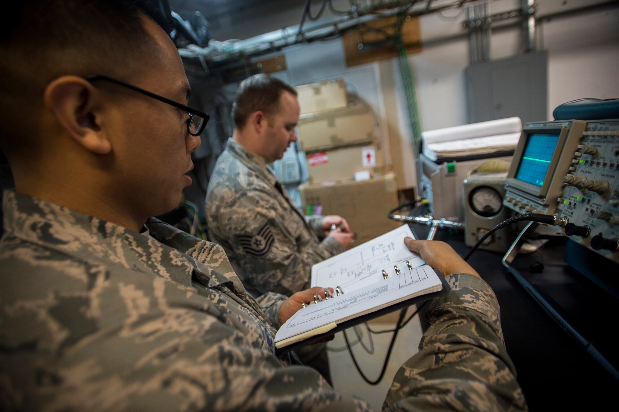 Staff Sgt. Michael Reyes, 437th Operations Support Squadron airfield systems technician, reads a technical order to Tech. Sgt. Shawn Arnett, 437th OSS airfield systems technician Jan. 27, 2016, at the command tower on Joint Base Charleston – North Auxiliary Air Field, S.C. This two-man team ensures that all of their airfield systems located at North Field work properly and provide any maintenece when needed. (U.S. Air Force photo/Senior airman Clayton Cupit)