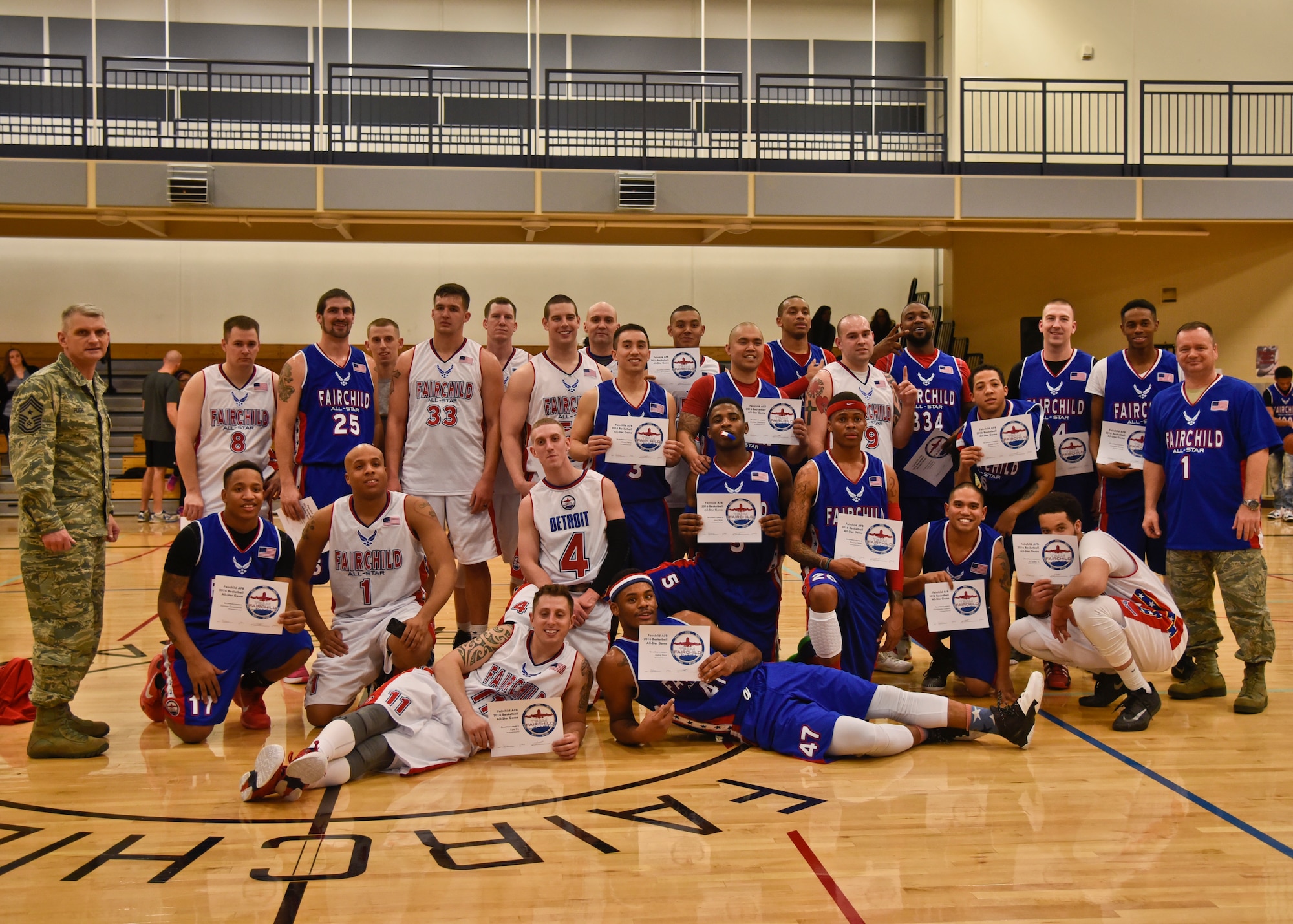 Members from the Blue and White All-Star teams pose for a photo with their coaches Col. Brian McDaniel, 92nd Air Refueling Wing commander (blue team), and Chief Master Sgt. Christian Pugh, 92nd ARW command chief (white team), after the first All-Star game Feb. 3, 2016, at Fairchild Air Force Base, Wash. A 3-point shootout contest kicked off the first all-star game. A slam dunk contest was also held during halftime. White team won with an ending score of 83-79. (U.S. Air Force photo/Airman 1st Class Taylor Bourgeous)