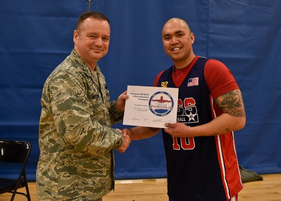 Col. Brian McDaniel, 92nd Air Refueling Wing commander, presents a certificate to Senior Airman Jan Michael Obiniana, 92nd Force Support Squadron intramural sports director, for winning the 3-point shootout competition during the first All-Star Basketball game Feb. 3, 2016, at Fairchild Air Force Base, Wash. Obiniana made 17 3-point shots in the allowed time, earning him the title of 3-point shootout champion. (U.S. Air Force photo/Airman 1st Class Taylor Bourgeous) 
