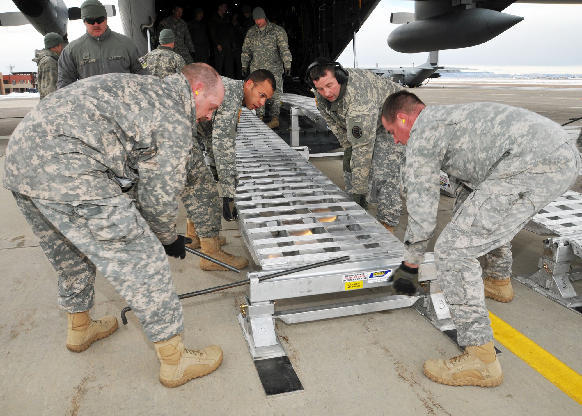 Members of the 83rd Civil Support Team and 120th Airlift Wing of the Montana National Guard place a ramp onto a C-130 Hercules Jan. 21, 2016. The guardsmen were exercising the loading of CST equipment and vehicles in the event they have to transport the equipment in an actual state or federal emergency. (U.S. Air National Guard photo by Senior Master Sgt. Eric Peterson/Released)