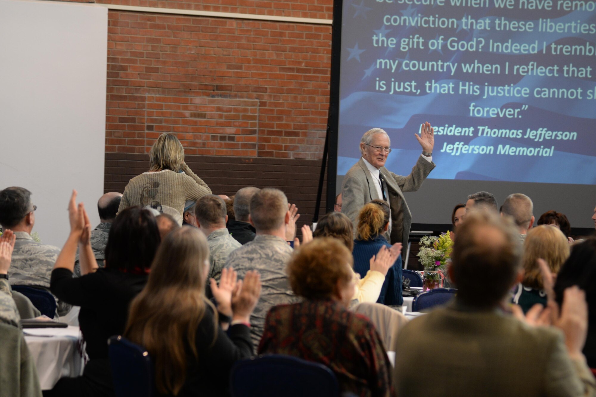 Retired Brig. Gen. Charles Duke Jr. waves to people from the Warren community and guests from the local community, who attended this year’s Prayer luncheon, Feb. 4, 2015, in the Fall Hall Community Center. The ceremony began with prayers from several religions including Jewish, Catholic and Protestant. (U.S. Air Force photo by Airman 1st Class Malcolm Mayfield)