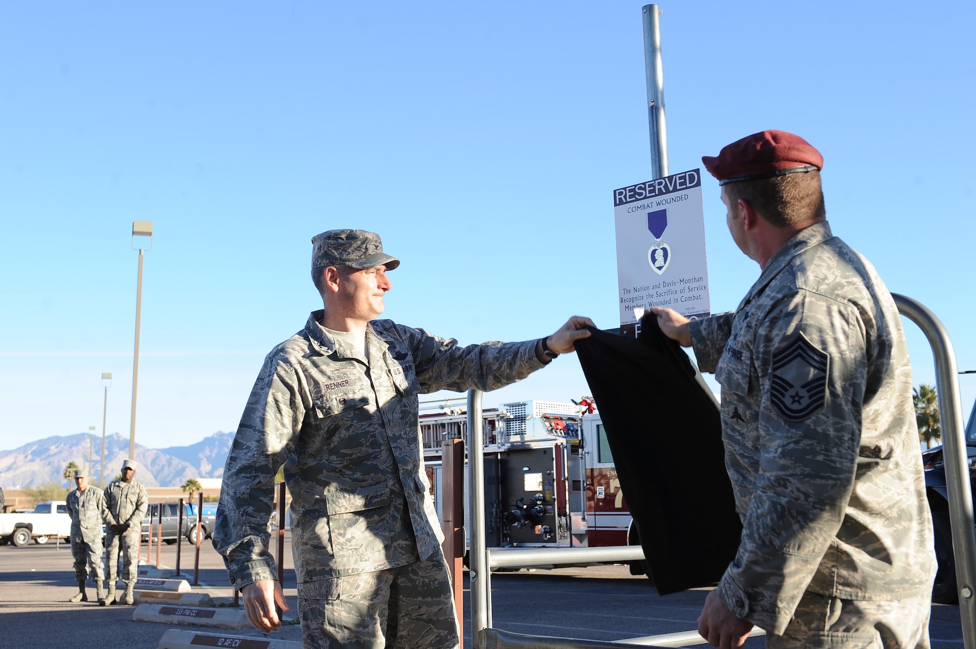 U.S. Air Force Col. Stephen Renner, 355th Fighter Wing vice commander, and Chief Master Sgt. Robert Disney, 48th Rescue Squadron superintendent, unveil the Purple Heart recipient reserved parking sign in the Exchange parking lot at Davis-Monthan Air Force Base, Ariz., Feb. 4, 2016.The sign was sponsored by the First Sergeants council who worked with multiple agencies around base to dedicate the parking space. (U.S. Air Force photo by Senior Airman Cheyenne A. Powers/Released)