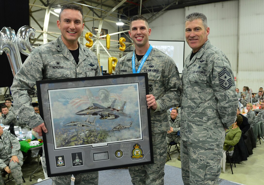 Col. Robert Novotny, 48th Fighter Wing commander, and Chief Master Sgt. David O’Hara, 48th Fighter Wing command chief, present the Airman of the Year Award to Senior Airman Matthew Dobbins, 48th Mission Support Group, during the 48th FW Annual Awards Banquet at Hangar 7, Feb. 5, 2016. Airmen were recognized across 13 categories, representing the spectrum of the Liberty Wing. (U.S. Air Force photo by Staff Sgt. Stephanie Longoria)