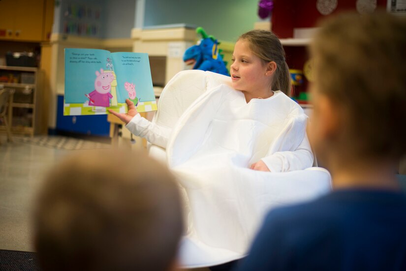 Samantha Holt, daughter of Capt. (Dr.) Melissa Holt, 779th Dental Squadron dentist, reads to children during a National Children's Dental Health Month event at the Child Development Center at Joint Base Andrews, Md., Feb. 5, 2016. During the event, members from the 779th DS spoke with children about proper brushing techniques, effects of too much sugar and healthy foods. (U.S. Air Force photo by Staff Sgt. Chad C. Strohmeyer/Released)