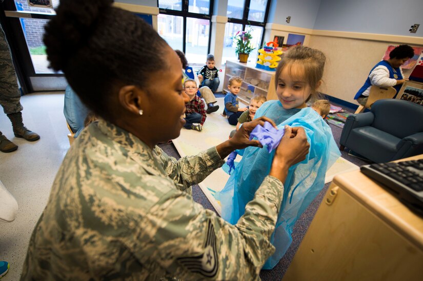Tech. Sgt. Tina Phelps-Prince, 779th Dental Squadron NCO in charge of preventive dentistry, helps a child put on dental gloves during a National Children's Dental Health Month event at the Child Development Center at Joint Base Andrews, Md., Feb. 5, 2016. During the event, members from the 779th DS spoke with children about proper brushing techniques, effects of too much sugar and healthy foods. (U.S. Air Force photo by Staff Sgt. Chad C. Strohmeyer/Released)