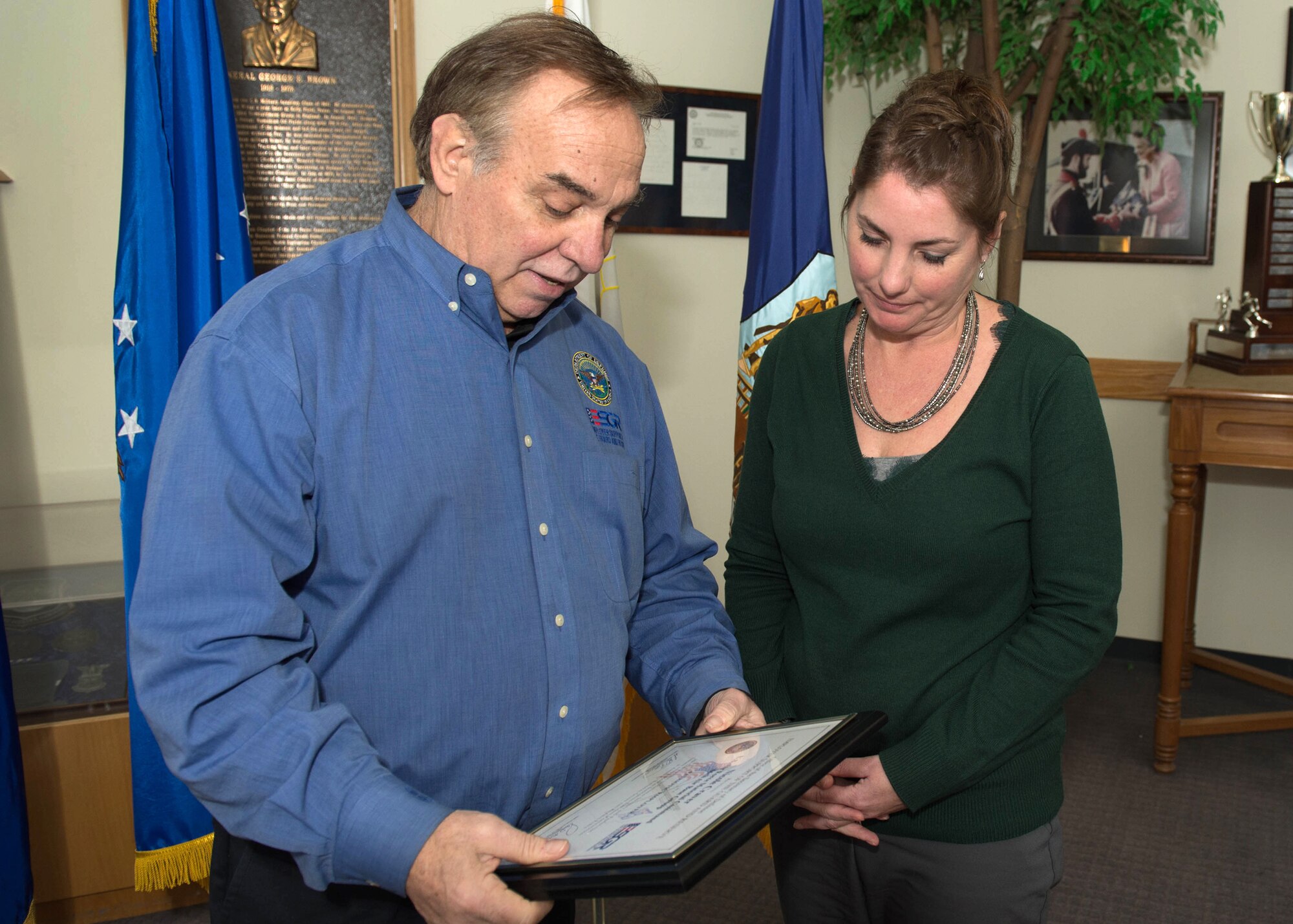 George Charos, Employer Support of the Guard and Reserve local chair, presents a plaque to Nicole Craver, 66th Force Support Squadron Human Resource officer, in the Brown Building lobby Feb. 4. Craver, formerly of the 66th Civil Engineering Division, was nominated by Paul Benenato, CE services contract manager, when the two worked together in CE. Benenato nominated Craver for her support to him as a member of the Army Reserves. (U.S. Air Force photo by Jerry Saslav)