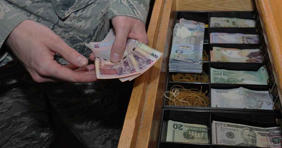 Senior Airman Bryan Hersey, 379th Expeditionary Comptroller Squadron cashier from Lompoc, California, counts Qatari Riyal while working inside the cashier cage at Al Udeid Air Base, Qatar, Jan. 24. Hersey said one of the most popular services the 379 ECPTS provides is currency exchanges and he's disbursed more than $4 million over the past six months. He said he loves his job because he enjoys helping people. (U.S. Air Force photo by Tech. Sgt. James Hodgman/Released)