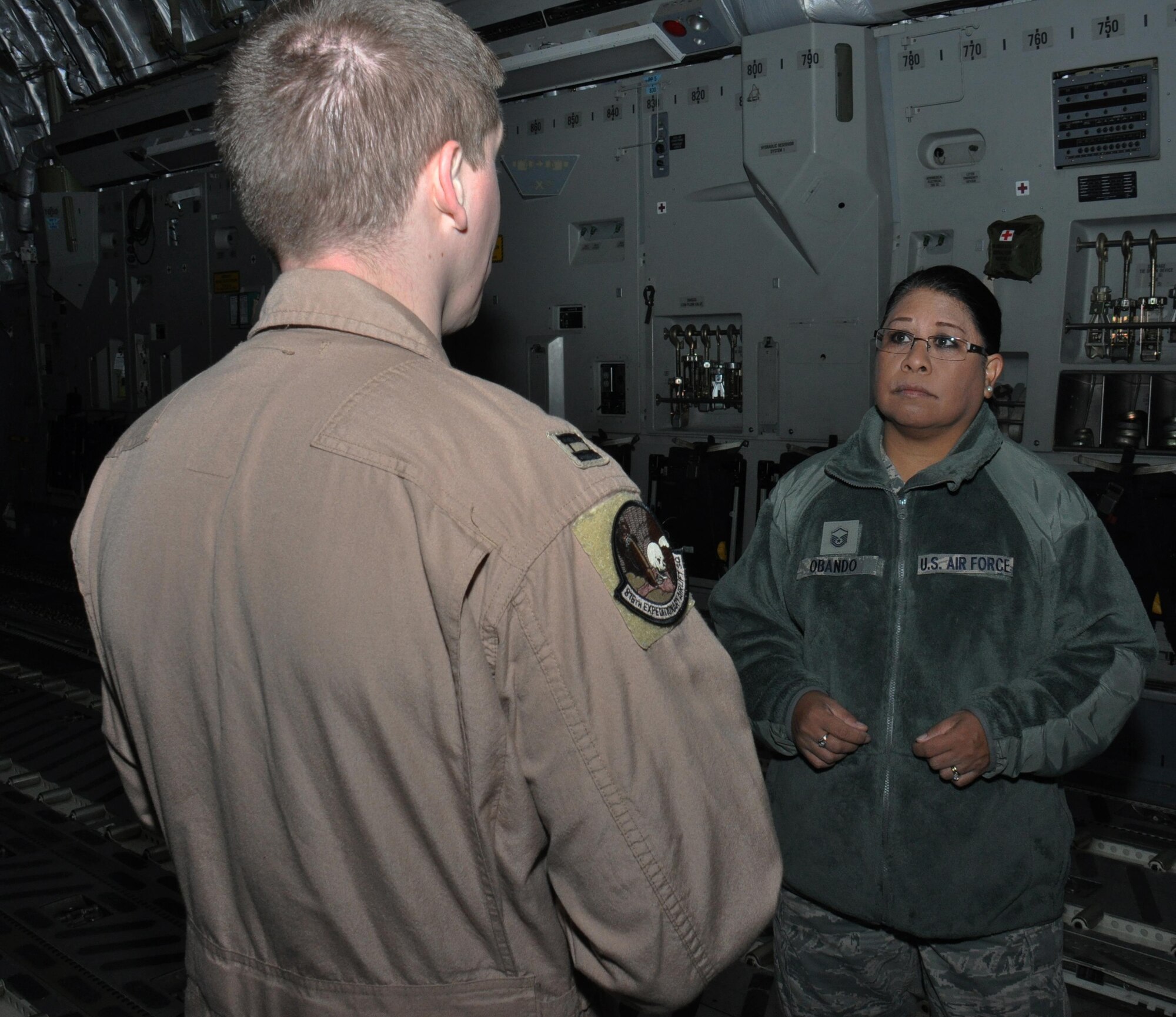Master Sgt. Janine Obando, 379th Air Expeditionary Wing Equal Opportunity Office director, listens to Capt. Brian, an 816th Expeditionary Airlift Squadron C-17 Globemaster III pilot, explain some of the capabilities of a C-17 Globemaster III during a tour of the aircraft Jan. 29 at Al Udeid Air Base, Qatar. As the 379 AEW's EO director, Obando is required to visit with commanders and airmen in their work centers to ensure they know the services the EO office provides. Brian is an aircraft commander deployed from Dover Air Force Base, Delaware. (U.S. Air Force photo by Tech. Sgt. James Hodgman/Released)