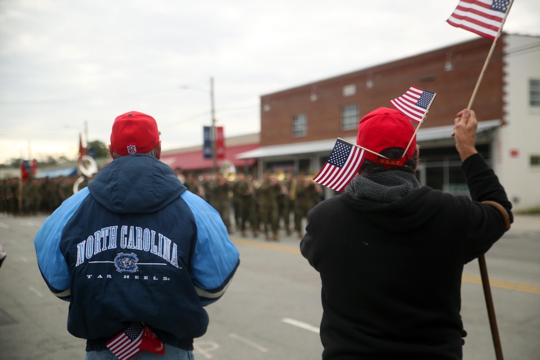 Veteran Marines wave American flags as active-duty service members with 2nd Marine Division march in the Division’s 75th anniversary parade in downtown Jacksonville, N.C., Feb. 6, 2016. The celebration serves as a time to remember the Marines and sailors who served and continue to serve in 2nd Marine Division, while thanking the local community for their support. (U.S. Marine Corps photo by Cpl. Joey Mendez/Released)