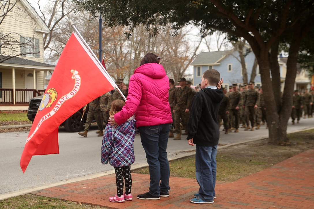 A family displays a United States Marine Corps flag to show support for 2nd Marine Division during the unit’s 75th anniversary parade in downtown Jacksonville, N.C., Feb. 6, 2016. The celebration serves as a time to remember the Marines and sailors who served and continue to serve in 2nd Marine Division, while thanking the local community for their support. (U.S. Marine Corps photo by Cpl. Joey Mendez/Released)