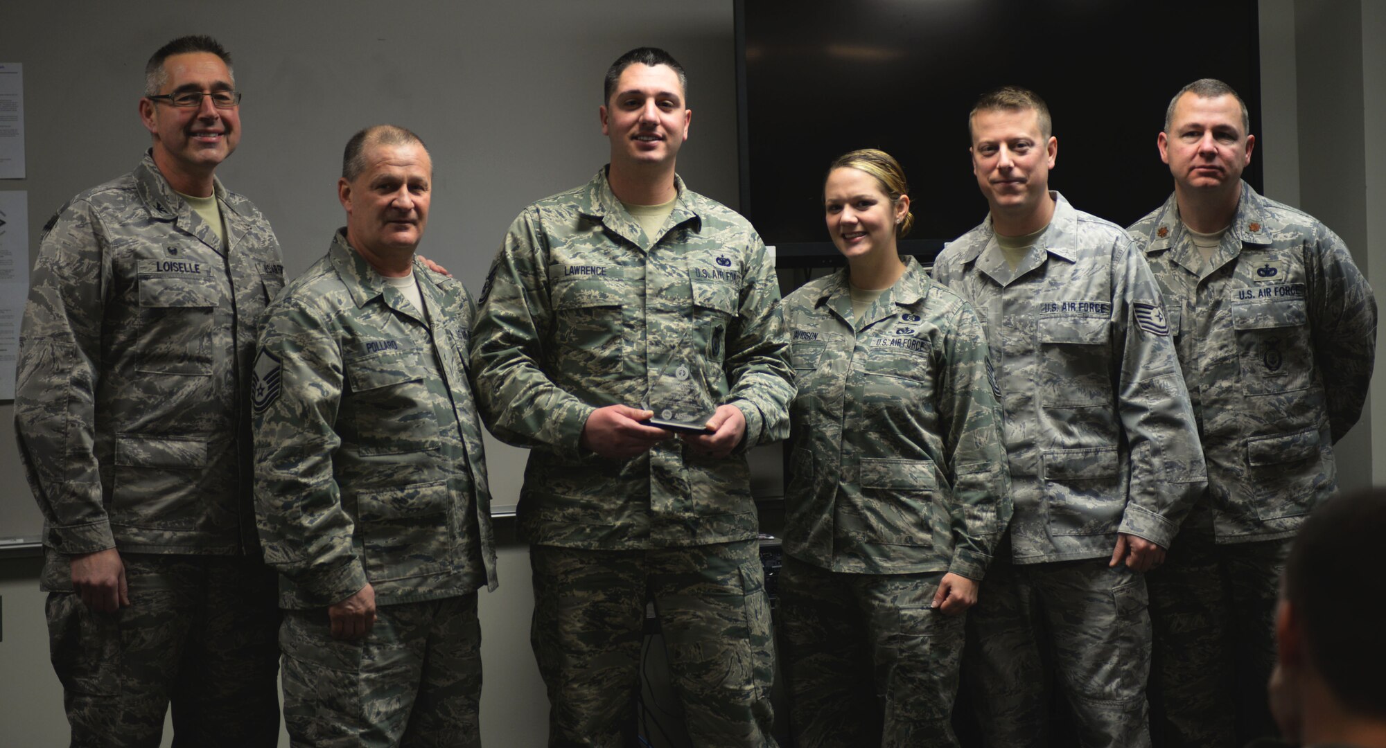 Staff Sgt. Paul Lawrence, (center), 157th Security Forces Squadron craftsman, was named the New Hampshire Air National Guard Unit Career Advisor (UCA) of the Year during the security forces roll call, Pease Air National Guard Base, N.H., Jan. 2, 2016. (U.S. Air National Guard photo by Senior Airman Kayla McWalter) 