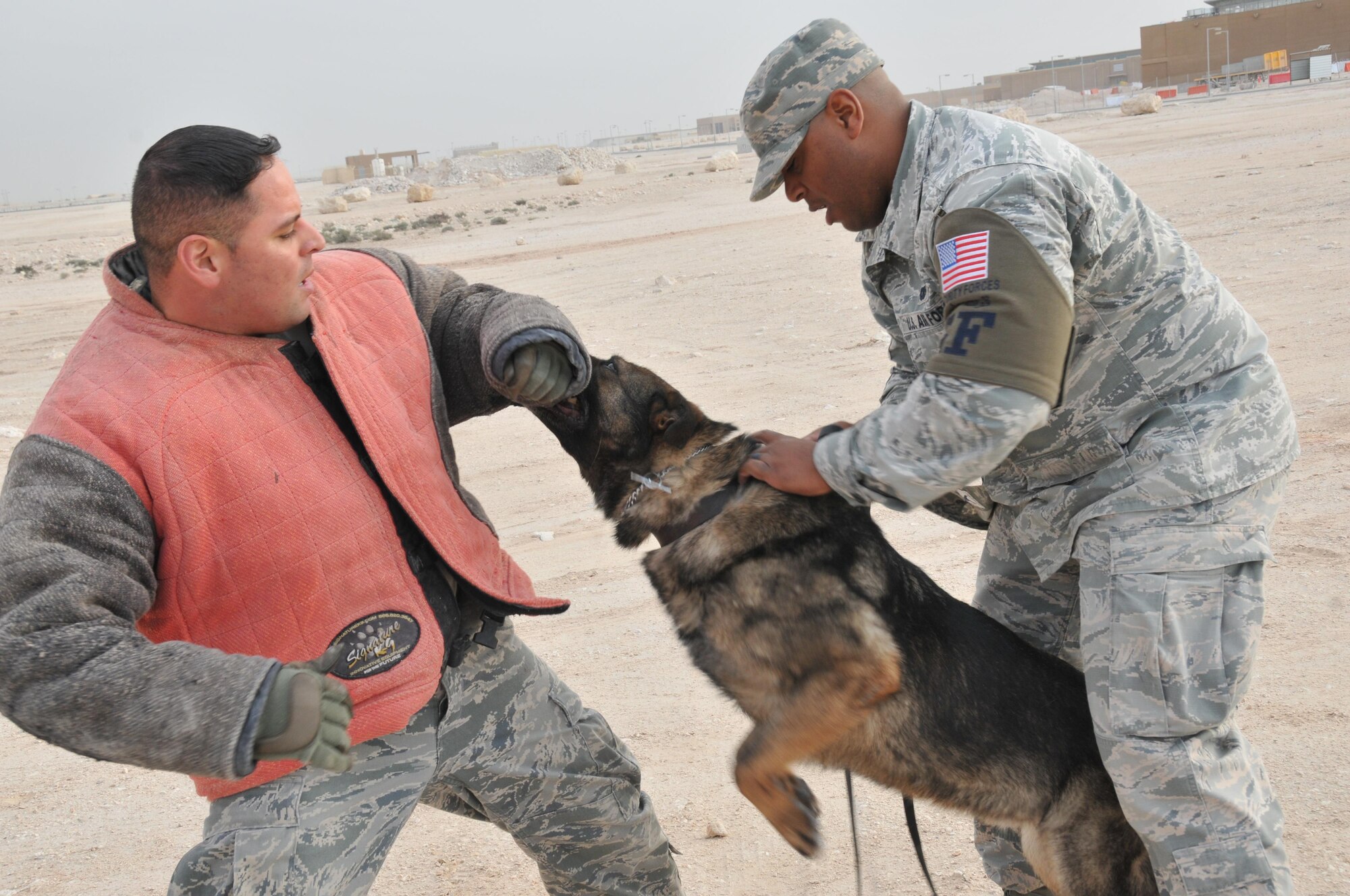 Tech. Sgt. Max Soto (left), 379th Expeditionary Security Forces Squadron military working dog trainer and Staff Sgt. Jahmal Hardy (right), 379 ESFS MWD handler, and Nero, his partner, practice patrol training Jan. 27 at Al Udeid Air Base Qatar. A part of patrol training is to apprehend and locate suspicious individuals. (U.S. Air Force photo by Tech. Sgt. Terrica Y. Jones/Released)
