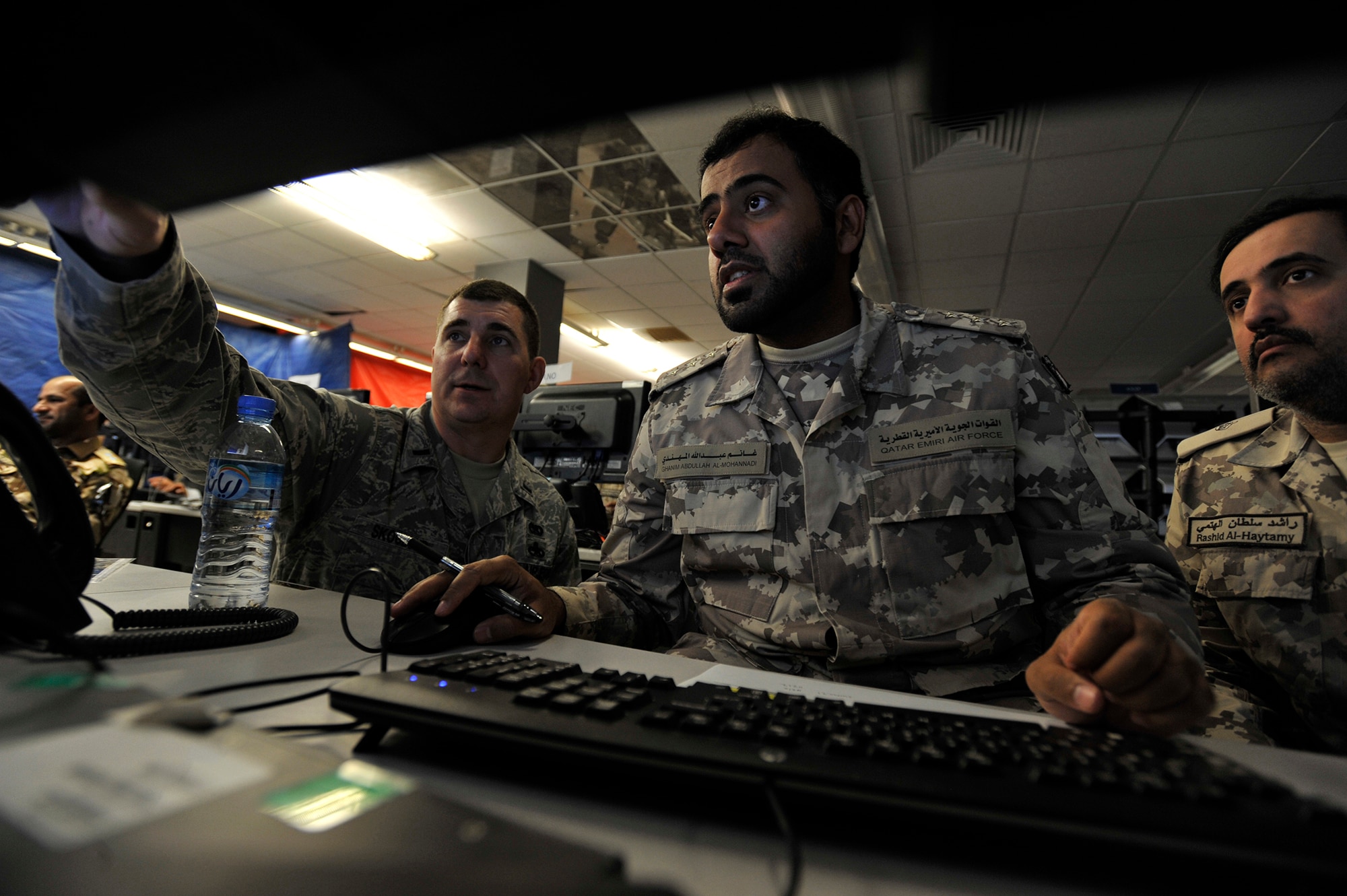 1st Lt. Joshua Skoglund, exercise coordinator, assists Qatar Emiri Air Force Capt. Ghanim Al-Mohannadi and Maj. Rashid Al-Haytamy during Arabian Gulf Shield, Feb. 3, 2016, in the Combined Air Operations Center, Al Udeid Air Base, Qatar. Arabian Gulf Shield is the culminating exercise for the Gulf Cooperation Council (GCC) Liaison Officer (LNO) Program. The exercise is designed to exercise GCC LNO procedures and connectivity to host nation Air Operations Centers which improves US-GCC interoperability. (U.S. Air Force photo by Master Sgt. Joshua Strang)