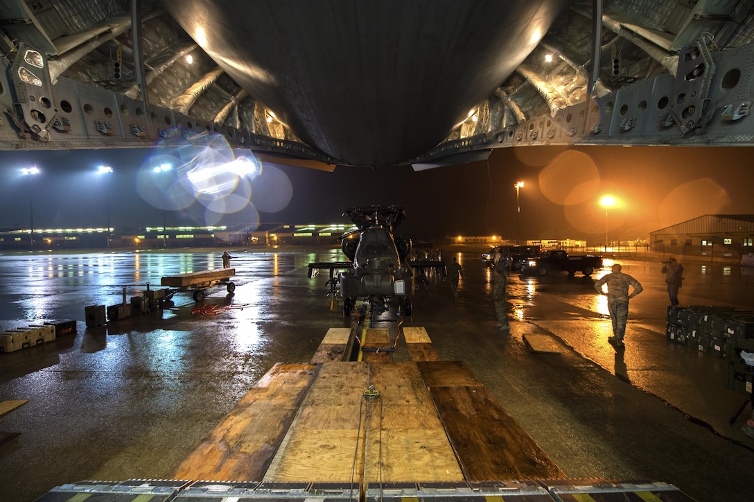 Soldiers and airmen work together to load an AH-64 Apache helicopter onboard a C-17 Globemaster III in support of large package week operations on Pope Army Airfield, N.C., Feb. 4, 2016. Air Force photo by Staff Sgt. Paul Labbe