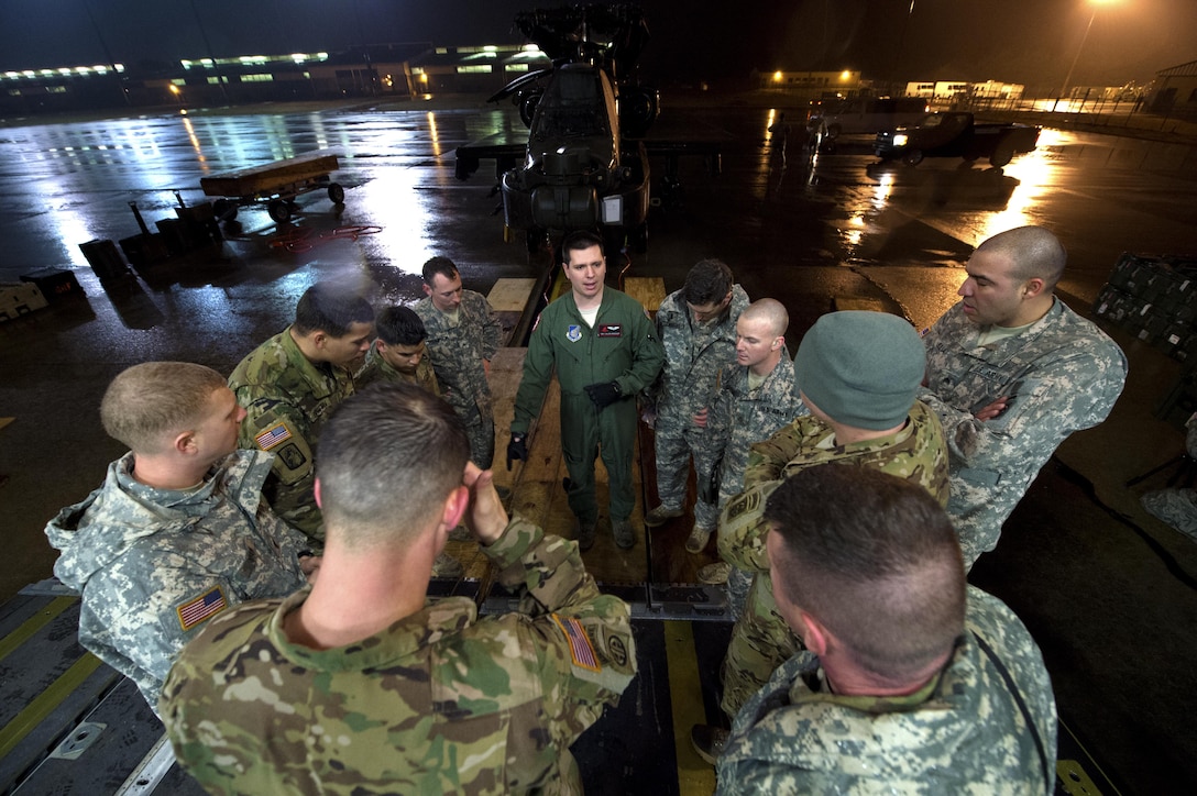 Soldiers and airmen receive a mission brief before working together to load an AH-64 Apache helicopter onboard a C-17 Globemaster III in support of large package week operations on Pope Army Airfield, N.C., Feb. 4, 2016. The soldiers are assigned to the 82nd Airborne Division’s 82nd Combat Aviation Brigade and the airmen are assigned to the 517th Airlift Squadron, 3rd Airlift Wing deployed from Joint Base Elmendorf-Richardson, Alaska. The training prepares Army and Air Force units for worldwide crisis and contingency operations. Air Force photo by Staff Sgt. Paul Labbe