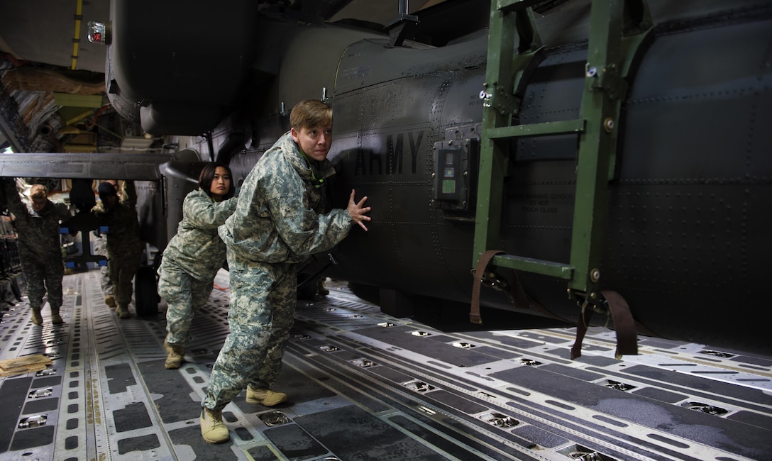 Soldiers and airmen work together to upload an AH-64 Apache helicopter onboard a C-17 Globemaster III in support of large package week operations on Pope Army Airfield, N.C., Feb. 4, 2016. Air Force photo by Staff Sgt. Paul Labbe
