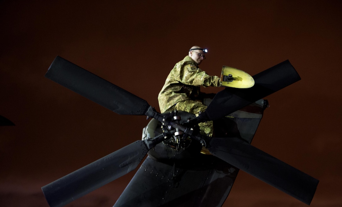 A soldier works on the tail rotor of an AH-64 Apache helicopter before being loaded up inside a C-17 Globemaster III in support of large package week operations on Pope Army Airfield, N.C., Feb. 4, 2016. Air Force photo by Staff Sgt. Paul Labbe